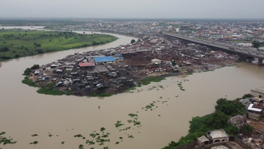 Cars moving speedily on brown river bridge of a sub-urban highway. a swampy area inhabited y locals