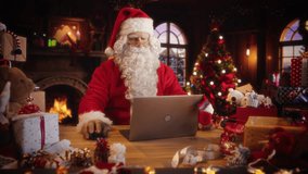 Merry Santa Claus Sitting Behind a Desk and Working on Laptop Computer. Senior Santa Shopping Online, Fulfilling Gift Orders for Christmas and New Year. Advertising Footage for Winter Holidays - Powered by Shutterstock - Get 15% off with code: PIKWIZARD15