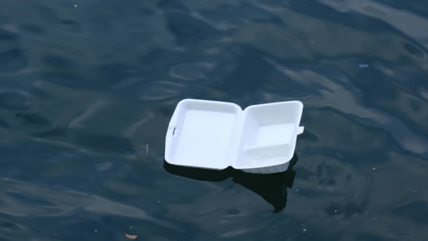 Close up a foam food container floating at the sea. Environment pollution concept.