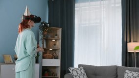 holiday online, young woman with a festive cap in virtual reality glasses congratulates her friends on video call, standing in cozy room - Powered by Shutterstock - Get 15% off with code: PIKWIZARD15