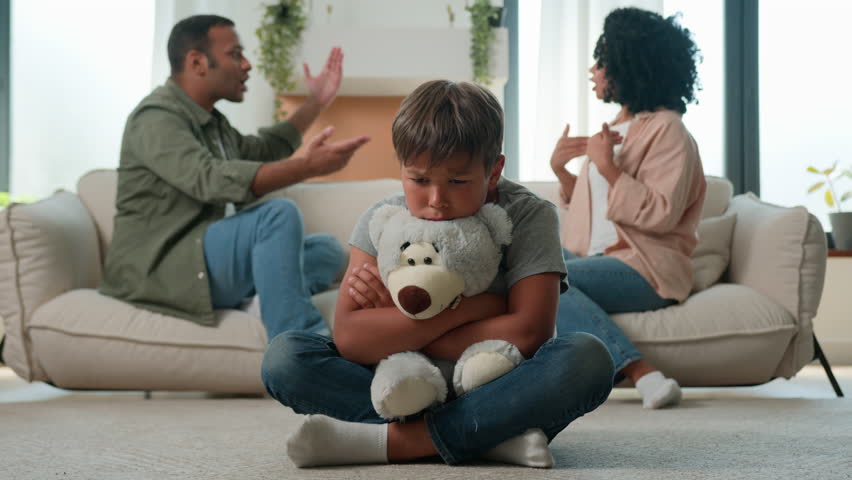 Upset Caucasian little boy preschool son hug teddy toy while African American woman mother and man father in anger screaming arguing background sad kid suffer from family quarrel conflict child trauma Royalty-Free Stock Footage #1109550533