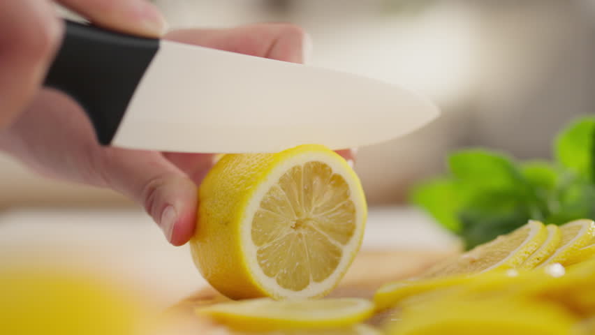 Freshness. A woman with a belly confidently cuts a fresh lemon in a housewife's home kitchen. Concept housewife woman hands cutting lemon applies cutlery, ingredient