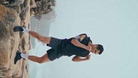 Professional athlete punch air on seaside cliff vertical. Strong boxer training on rocks practicing in cloudy morning. Focused strong man kickboxing prepare for fight battle. Sport video tutorial