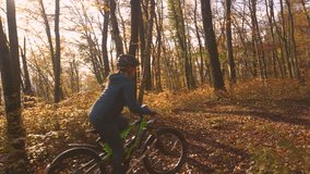SLOW MOTION: Lady riding electric bike through autumn forest with dog by her side. They are exploring colorful and magical woods while moving along a path strewn with fallen tree leaves on sunny day. - Powered by Shutterstock - Get 15% off with code: PIKWIZARD15