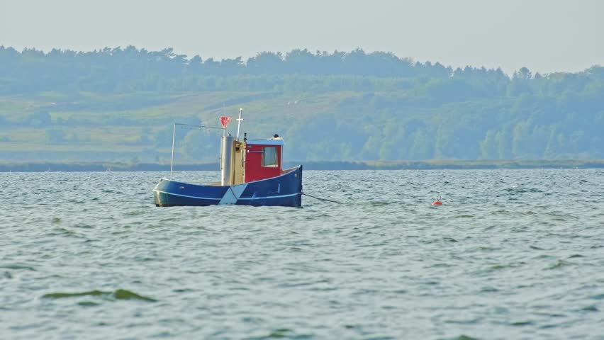 Small Fishing Sea Motor Boat Anchored in Bay on Windy Day