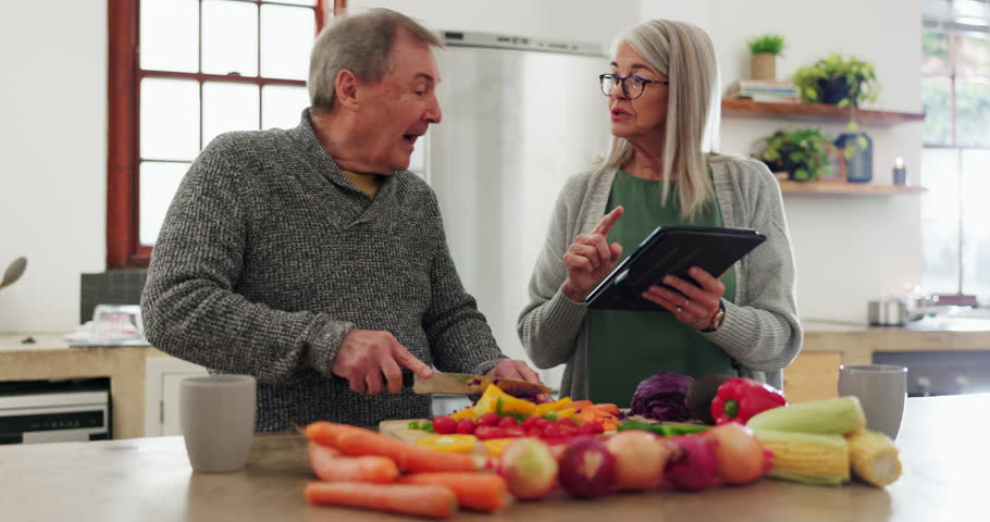 Senior couple in kitchen, cooking with tablet and help with online recipe for vegetable dinner. Healthy food, old man and woman in home checking digital app on meal prep, diet planning and lunch chat