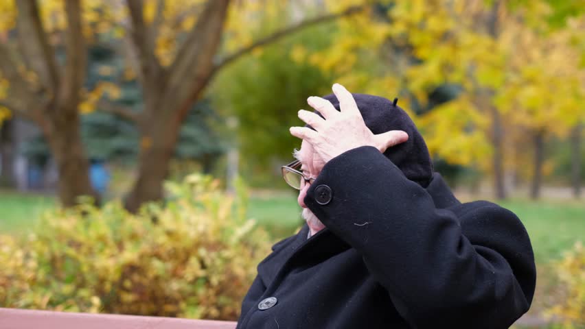 Grandfather in a black beret sitting on a bench in an autumn park. The concept of recreation