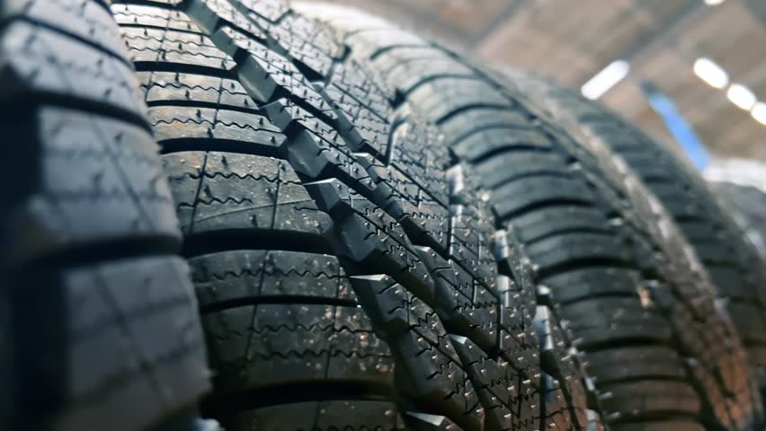 Rows of new car tires line the shelf at the auto store. Close up