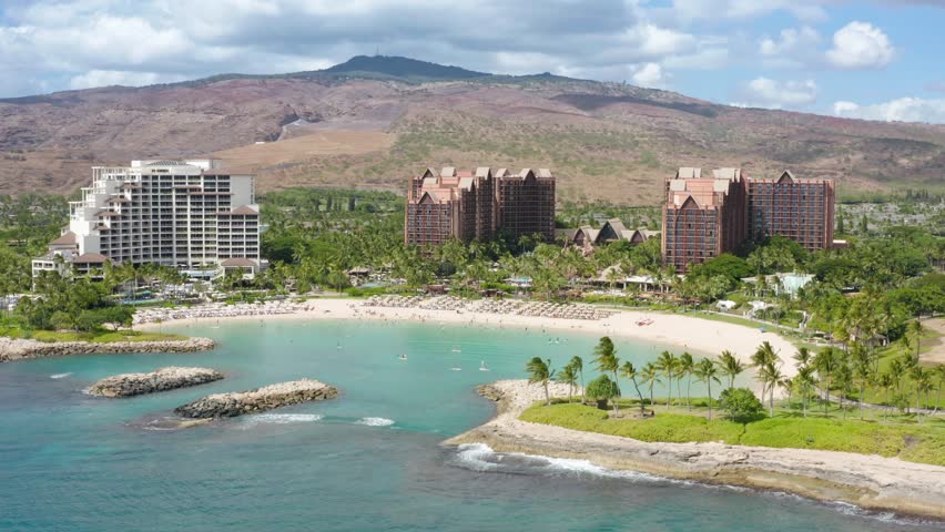 Drone shot family hotel with scenic blue lagoon view. Cinematic shot on Ko Olina resorts on Oahu island Hawaii USA tourism. Palm trees exotic travel paradise 4K. Aerial view of luxury beachfront hotel