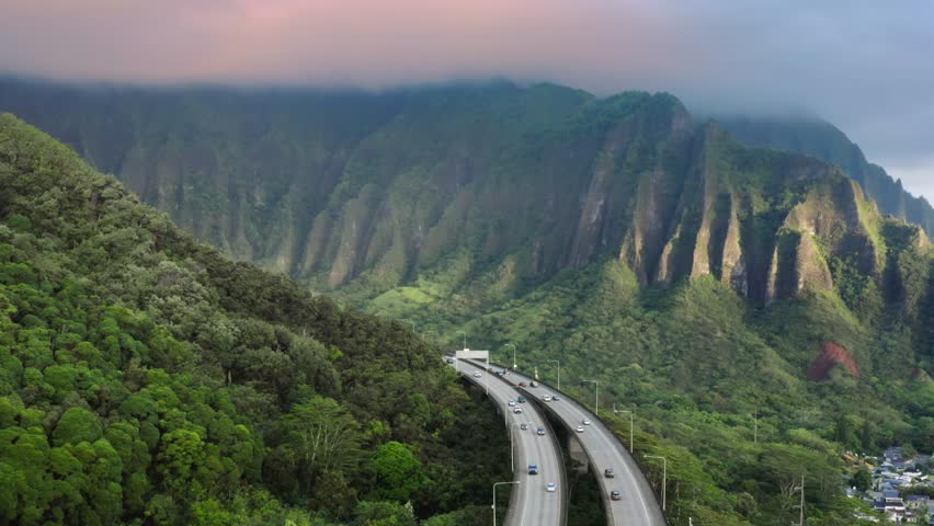Scenic route on Oahu Hawaii island at golden sunrise. Interstate H3 passing through majestic green Koolau Mountains with Trans-Koolau twin tunnels. Aerial along highway with epic nature landscape view