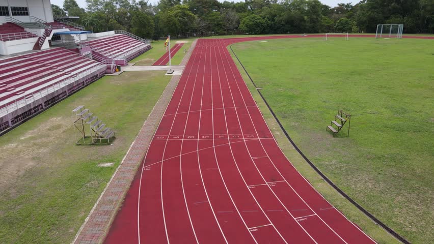 Sarawak, Malaysia – January 30, 2022: The aerial view reveals a vibrant standard red running track with clearly numbered lanes in stadium, ready to host athletic competitions and races.