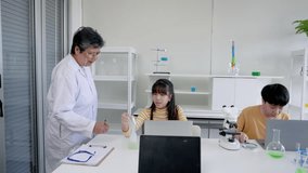 During elementary school science lessons, a senior science teacher Checking student experiment results that been recorded on laptop computer, when the students are taking exam and using the laptop - Powered by Shutterstock - Get 15% off with code: PIKWIZARD15
