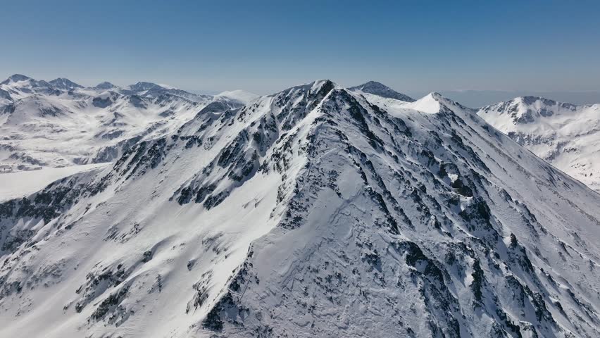 Aerial rising view Alps mountains snowy peaks in sunny day with high clouds. Majestic breathtaking mountains landscape. Drone Aerial Flight Over Swiss Mountain Range. Panoramic aerial footage