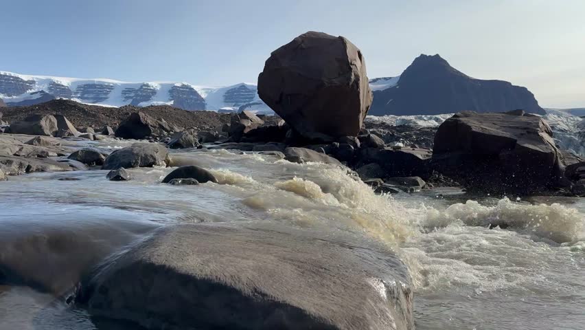 Panning view of Glacier meltwater flowing into the fjord in Terrassevig, Scoresbysund, Greenland.
