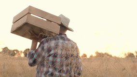 Horizontal shot. Portrait of senior farmer standing at wheat field. Man wearing straw hat and checkered shirt. Cheerful farmer in straw hat carrying wooden box. Agricultural products. - Powered by Shutterstock - Get 15% off with code: PIKWIZARD15