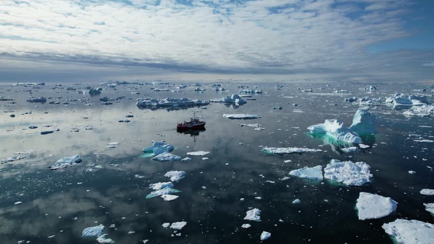 Transportation ship sailing near icebergs in deep ocean, aerial view