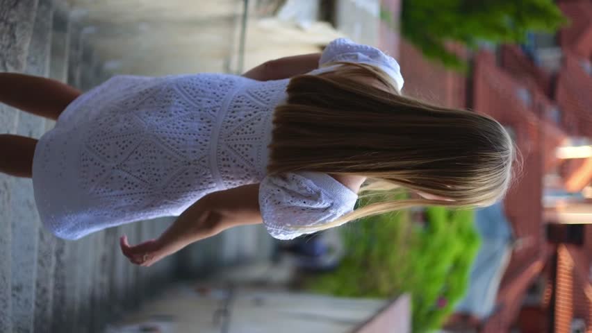 Young woman walking at downtown of Prague. Back view elegant lady goes down stairway leading to Prague castle
