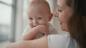 Portrait of happy family affectionate positive mom kissing baby holding in hands looking at window. Mother kisses kid at home. Motherhood, parenting, babycare, childhood, babyhood, love care concept. - Powered by Shutterstock - Get 15% off with code: PIKWIZARD15