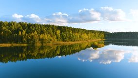 Aerial view of beautiful smooth green waters of a lake on a sunny autumn day. Bird's eye view of scenic emerald lake surrounded by forests. Clouds reflecting in the water, golden foliage in fall. - Powered by Shutterstock - Get 15% off with code: PIKWIZARD15