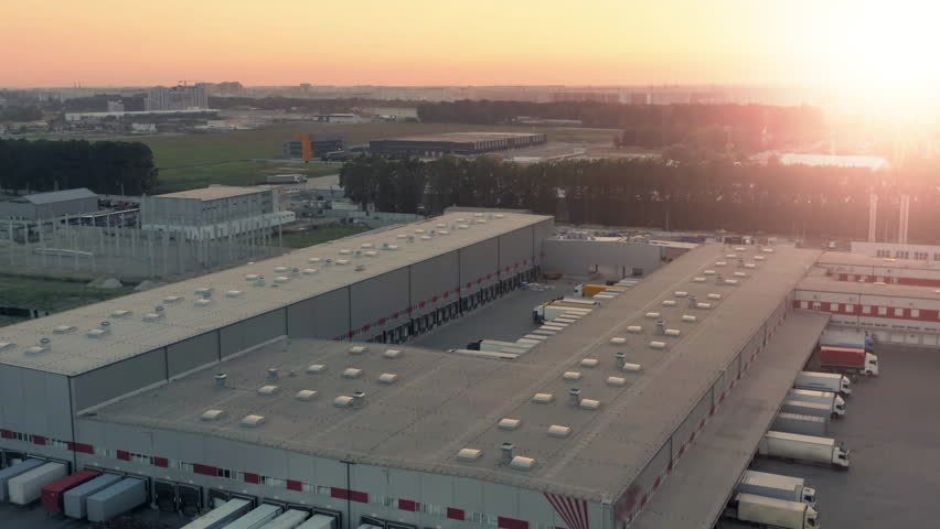 Aerial view of a large modern logistics park with warehouses at sunset. Semi-trailers trucks standing at ramps for unloading and loading goods Royalty-Free Stock Footage #1109599749