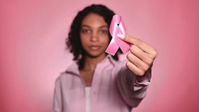 Breast cancer awareness concept.Smiling,cheerful girl with pink ribbon on pink background.October - Powered by Shutterstock - Get 15% off with code: PIKWIZARD15