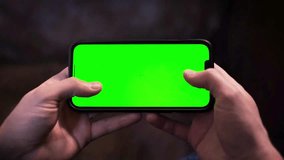 Slow motion of male hand playing a video game on his smartphone. Close-up of fingers clicking, touching on a green screen with tracking markers. Using modern device, app template, cyber gaming concept