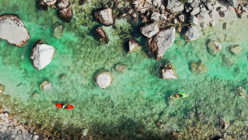 Kayakers on Soca river in Slovenia. Aerial top down tracking shot. Two kayaks on the emerald alpine water of Soca mountain river in Slovenia, Triglav National Park. 