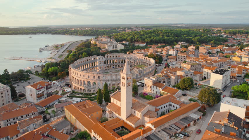Flying over Croatian city of Pula at sunset. Aerial view of the historic Roman Amphitheatre of Pula, Istria Peninsula. Ruins of the Roman Colosseum Arena in Pula, Croatia. UNESCO World Heritage site Royalty-Free Stock Footage #1109611141