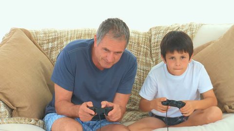 A child playing video games with his grandfather on the sofa