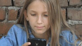 Child Playing on Smartphone in Park, Kid Browsing Internet on Smart Phone, Blonde Teenager Girl Typing Messages Talking on Device
