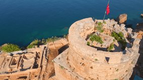 Enjoy a breathtaking view of Hidirlik Tower, an iconic symbol of Antalya's historical center, in this mesmerizing aerial stock video. The tower, with its ancient charm and stunning location