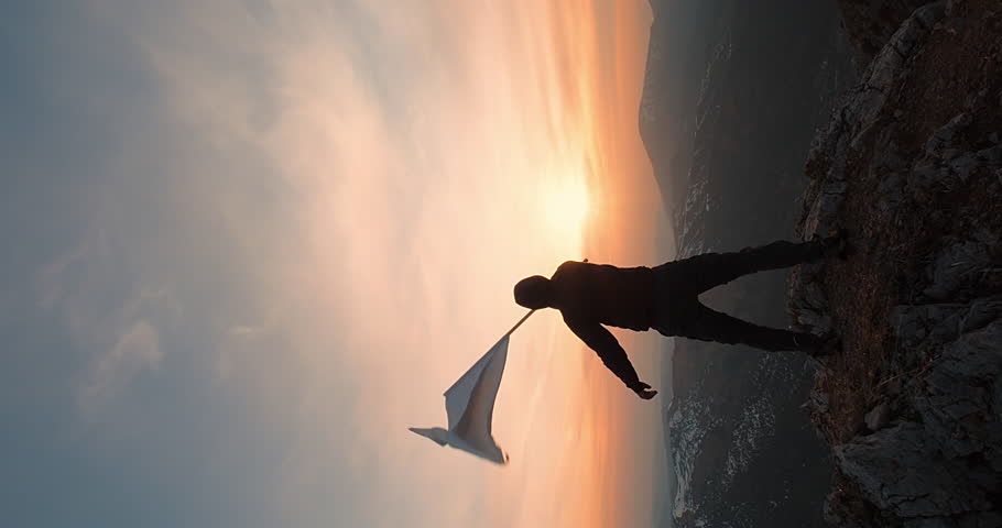 Say No to War, Vertical shot of a Strong Man on Top of a Mountain with Cinematic Sunset Background Waving a White Flag while the Wind Blows. Concept of World Peace, Conquering Goals and Dreams.. Royalty-Free Stock Footage #1109627913