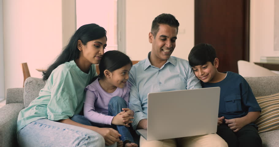 Happy Indian family with little adorable son and daughter relaxing at home, watching online movie, spend free time together, enjoy cartoons seated on cozy couch with laptop. Family leisure on internet Royalty-Free Stock Footage #1109628271