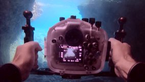 POV underwater shot, Cameraman swims underwater holding camera housing in his hands and films video swimming in cave. First person view, Slow motion, Mediterranean sea