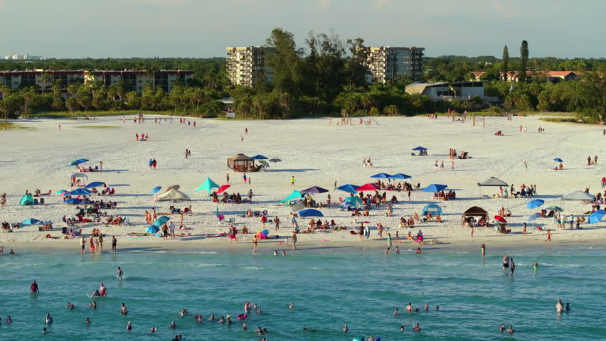 Famous Siesta Key beach with soft white sand in Sarasota, USA. Many people enjoying vacation time bathing in warm gulf water and tanning under hot Florida sun