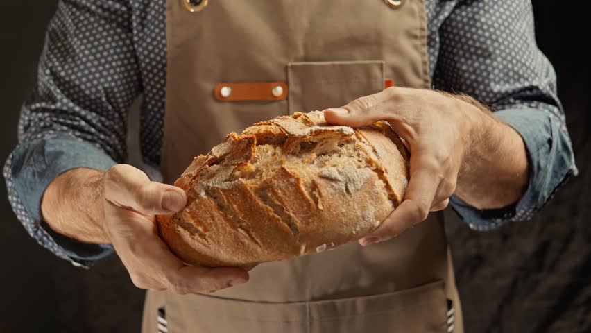 Baker hands breaking bread. Homemade bread breaking. Craft organic bread. Male baker hands breaking homemade bread. Bakery concept. Close-up in 4K, UHD