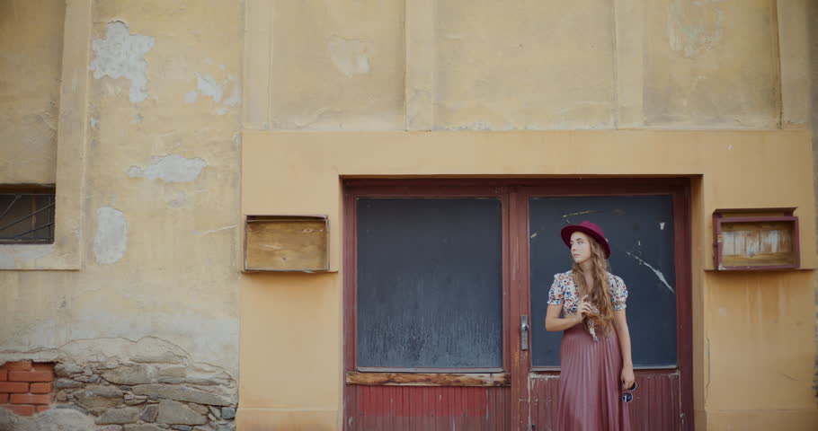 Fashionable young woman looking around while standing against building in town