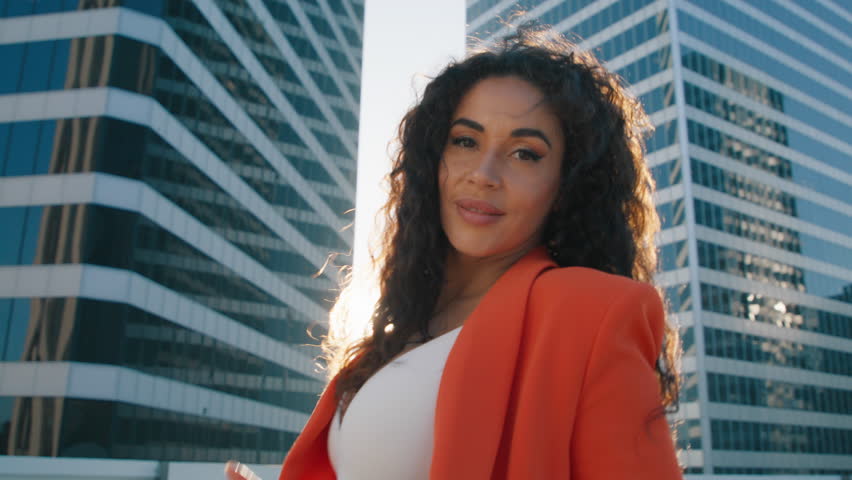 Fun happy young girl with hair flying sending air kiss. Attractive flirting young lady turns around and looks in camera. Beautiful sexy woman with magnificent long loose curly black hair