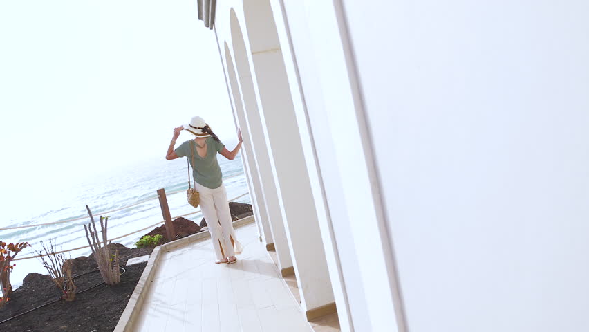 Mediterranean luxury hotel spa with ocean view being enjoyed by elegant mature female wearing sunhat travel tourism Europe