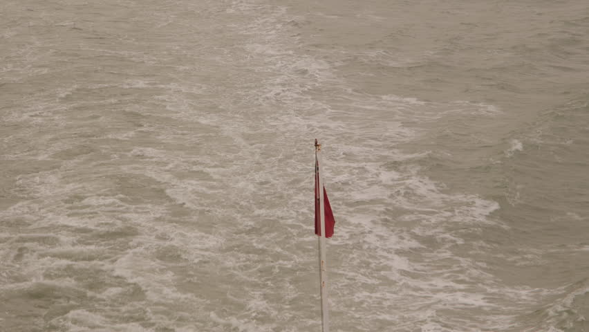 Red Ensign flies from the aft of a departing cross channel ferry in Dover, England