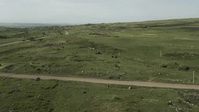 Drone video. Views near the monument to the Armenian alphabet in Artashavan village. Camera moves around the hills with green grass. A view of an empty road and the high snow-covered mountain Aragats.