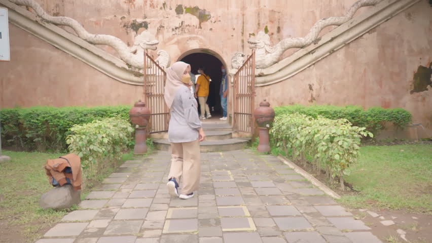 Female with mask persuading with gesture hand to enter a door to explore building
