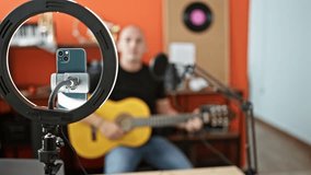 Young hispanic man musician recording video singing song playing classical guitar at music studio