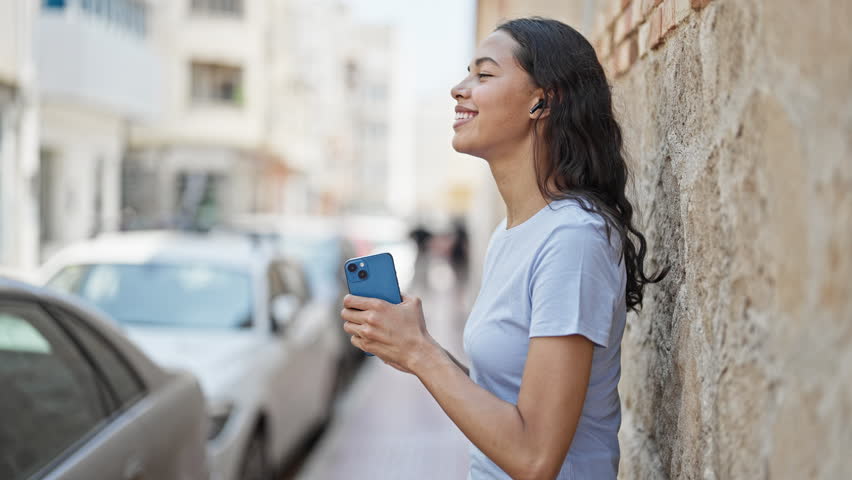 African american woman dancing listening to music on smartphone doing drummer gesture at street