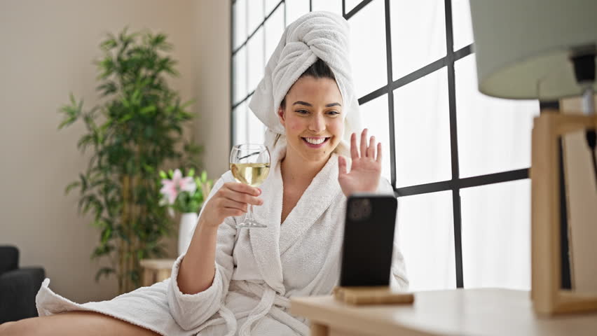Young beautiful hispanic woman wearing bathrobe drinking champagne having video call at bedroom Royalty-Free Stock Footage #1109655841