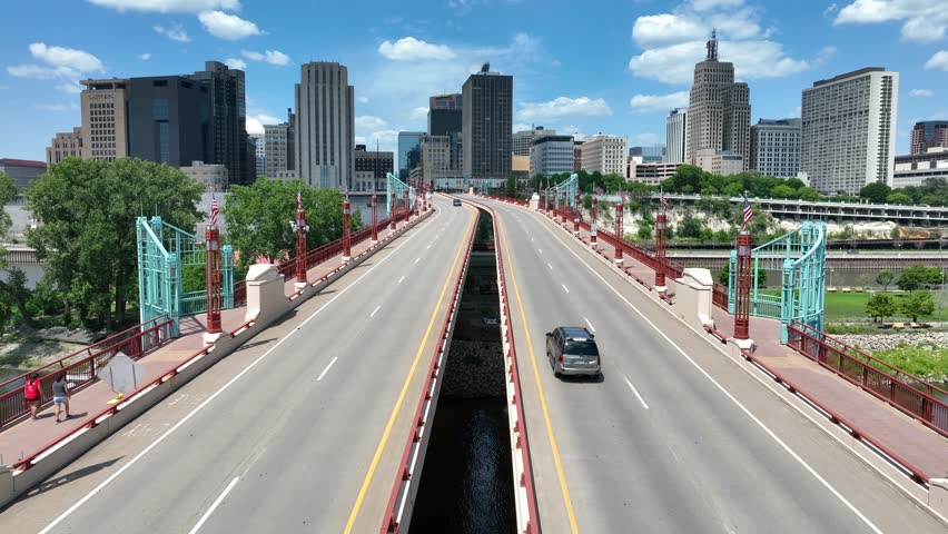 Wabasha Street Bridge in downtown Saint Paul, Minnesota. Aerial shot of cars crossing bridge with American flags. Overpass of Mississippi River and Raspberry Island on summer day.