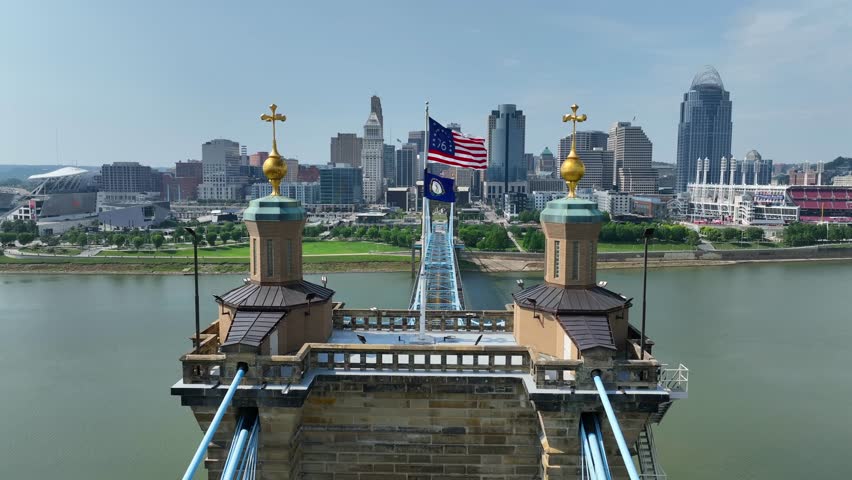 American Bennington Flag waving on bridge connecting Cincinnati, Ohio and Covington, Kentucky over Ohio River. Aerial establishing shot with Cincinnati skyline during summer day.