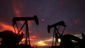 Oil pumps working at sunset on oil field, silhouettes of oil pump jacks mining energy from underground. - Powered by Shutterstock - Get 15% off with code: PIKWIZARD15