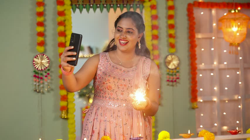 happy young girl playing with diwali crackers by talking on video call at home during diwali festival celebration - concept of long distance relationship, family connection and technology Royalty-Free Stock Footage #1109663453