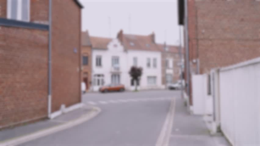 A lonely car drives along the street of a small French town. Background, blurry video.